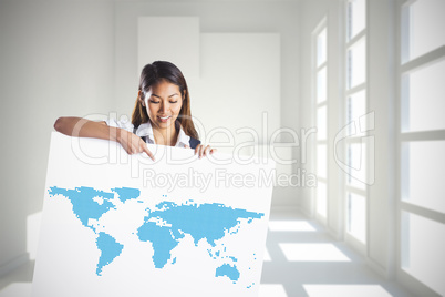 Composite image of smiling businesswoman pointing a white poster