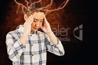 Composite image of asian man getting a headache