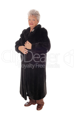 Senior woman standing in fur coat.