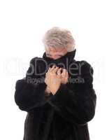 Senior woman hiding in her fur coat.