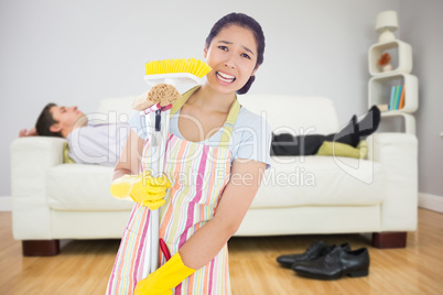 Composite image of distressed woman holding cleaning tools