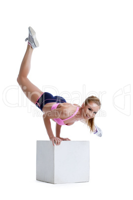 Cheerful fitness trainer exercising on cube