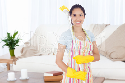 Composite image of smiling woman with a broom on her shoulder