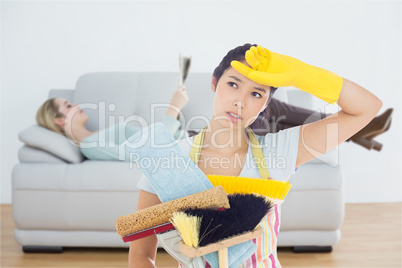 Composite image of weary woman holding cleaning tools