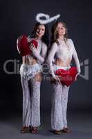 Charming girls posing in costumes of Cupids