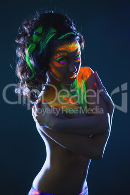 Topless girl posing with glowing UV makeup