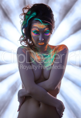 Naked young woman posing with glowing neon makeup
