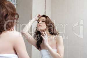 Beautiful girl admires her reflection in mirror