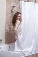 Shy smiling woman posing nude in shower