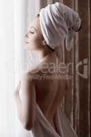 Seductive girl dressed in towel, posing at window