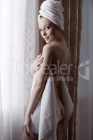 Beautiful girl posing naked hiding behind towel