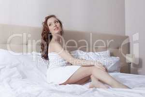 Image of curly brunette posing in hotel bed