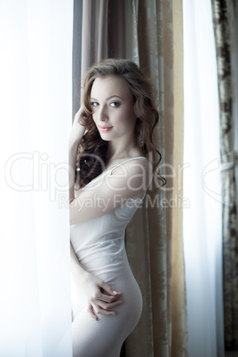 Charming model posing at window in hotel room
