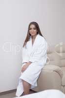 Image of pretty woman in bathrobe sitting on sofa