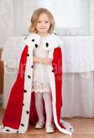 Smiling cute little girl posing in royal mantle