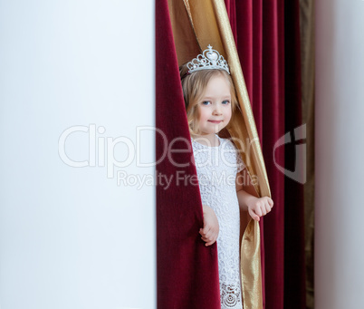 Image of adorable girl posing looking out curtains