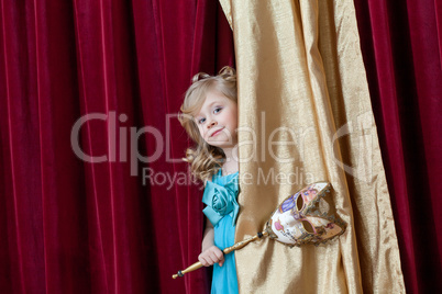 Cute curly-haired girl posing with carnival mask