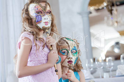 Cute sisters posing hiding faces behind masks