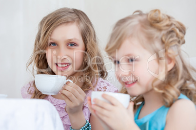 Studio shot of happy little girls drinking tea