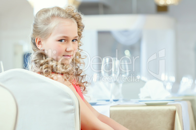Portrait of cute curly girl posing at table