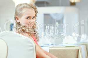 Portrait of cute curly girl posing at table