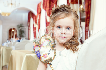 Lovely blue-eyed girl posing with carnival mask