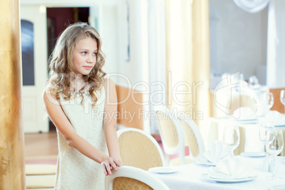Shy smart girl posing at table in restaurant