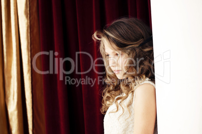 Charming girl shyly posing on curtain background