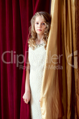 Charming curly girl posing on curtains background