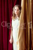 Charming curly girl posing on curtains background