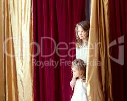 Beautiful girls look out from behind scenes