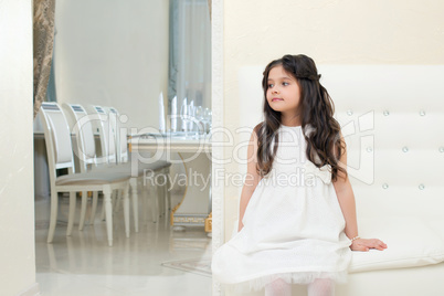 Pretty little girl posing while sitting on couch