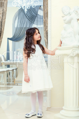 Cute little brunette looks at statue in restaurant