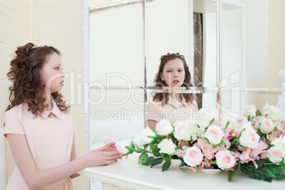 Cute little girl admiring her reflection in mirror