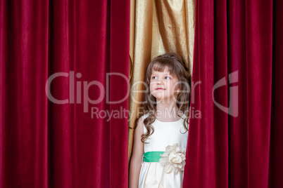 Pretty little brunette posing on curtain backdrop