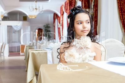 Gorgeous little girl posing at table in restaurant