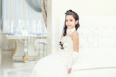 Lovely little girl posing in white luxurious dress