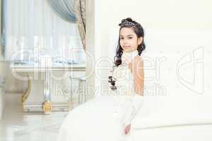 Lovely little girl posing in white luxurious dress