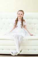 Funny little girl posing sitting on white couch