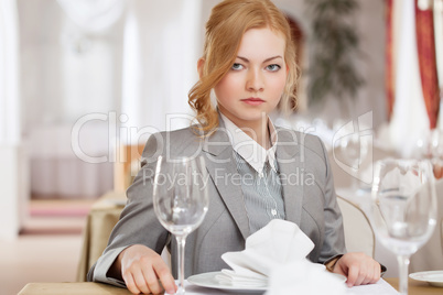 Serious red-haired business woman posing at table