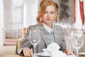 Serious red-haired business woman posing at table