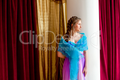 Beautiful elegant girl posing standing near column