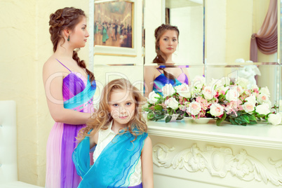 Cute elegant sisters posing before mirror