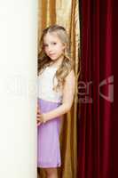 Cute curly girl posing on curtain backdrop