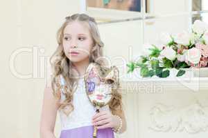 Shy little girl posing with masquerade mask