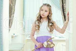 Little blue-eyed model posing with masquerade mask