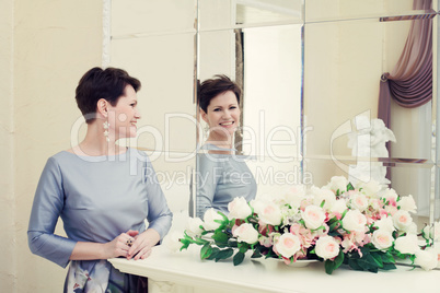 Cheerful middle aged woman laughing in mirror