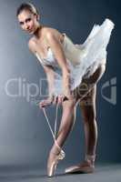Charming female ballet dancer posing tying pointe