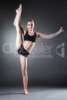 Smiling young woman posing on vertical splits