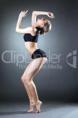 Slender young girl practicing gymnastics in studio